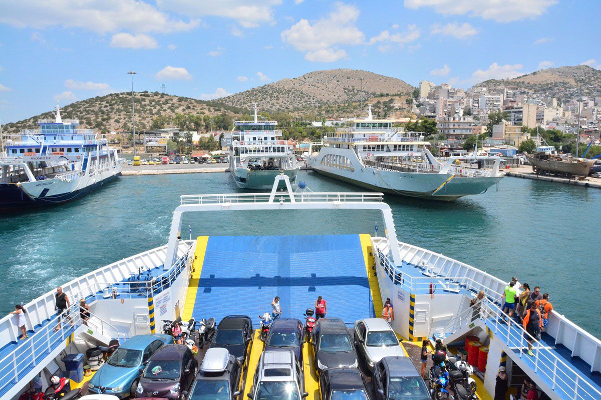 Photo of ferries with cars and people docking between two other ferries in the Greek isles.