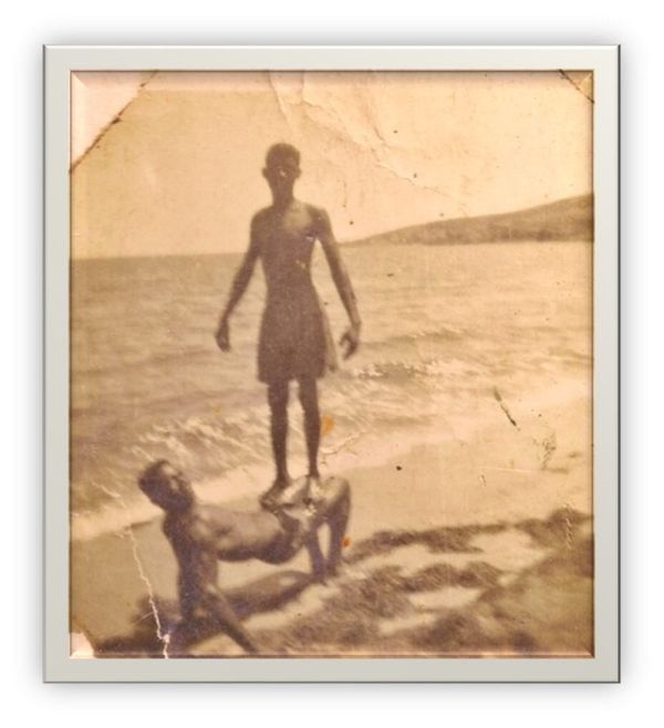 An old photo of two teenage males playing on a beach 