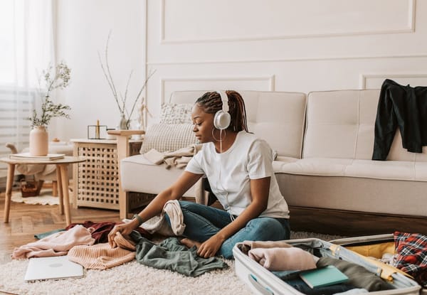 Woman packing her clothes in suitcase in her livingroom.