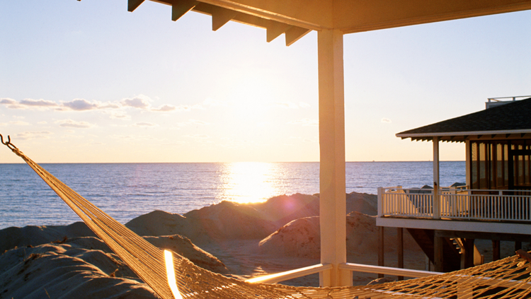 A serene beach scene with clear blue water, a hammock, on a beach front apartment, indicating relaxation and introspection.