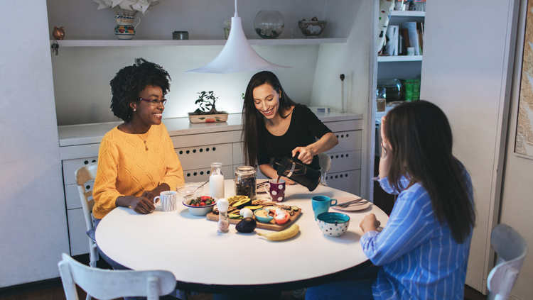 Three roommates having breakfast at a table and talking about protecting their money in uncertain times..